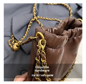 Detail der dunkelbraunen Ledertextur und der goldenen Kette an der Beuteltasche