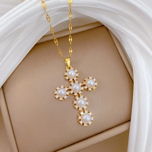 Close-up of gold titanium necklace with pearl cross pendant on luxury silk and velvet case