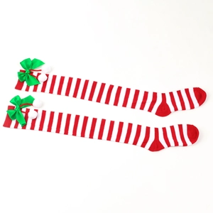 Detail of red and white striped Christmas over-knee socks with green bows and pom poms