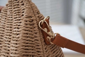 Detailed close-up of woven raffia texture with gold metal buckle and leather strap