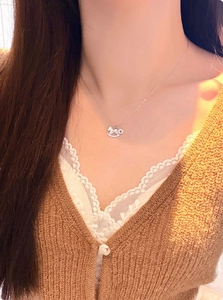 Silver rocking horse necklace with micro-pave crystals worn over a cozy sweater