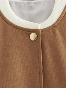Detail shot of a brown jacket featuring a white ribbed collar and a gold metal button