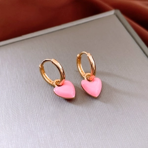 Macro shot of French vintage gold hoop earrings with pink enamel heart-shaped pendants