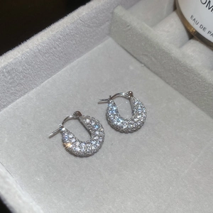 Detailed view of U-shaped silver earrings with sparkling cubic zirconia in a velvet box