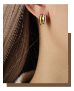 Close-up of elegant gold and silver two-tone geometric hoop earrings on female model