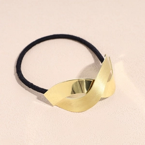 Detail of twisted gold metal cuff on black elastic hair tie for ponytail styling