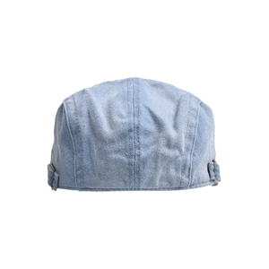 Detail of light blue washed denim beret featuring side bronze metal adjustment buckles