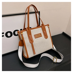 Detail view of the canvas tote bag with brown leather trim and adjustable strap