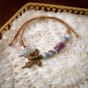 Detail of vintage ceramic beads and bronze butterfly charm on hand-woven bracelet