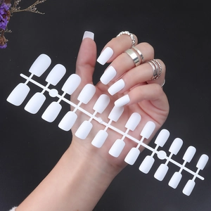 Close-up of 24 pieces of long square matte white false nail tips held by a hand