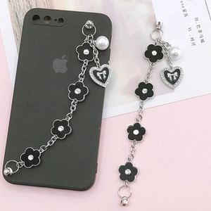 Detail of black heart and floral phone charms with faux pearls and silver chains