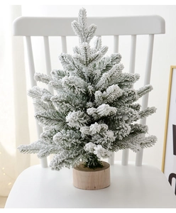 Close-up of a mini flocked Christmas tree with snow effect on a round wooden base