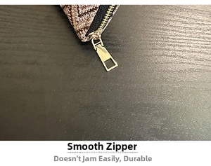 Detail view of the smooth golden metal zipper and brown geometric jacquard fabric