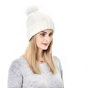 Close-up of white cable knit beanie with faux fur pom-pom detail and ribbed cuff