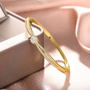 Detail shot of golden open bracelet featuring a round zircon and micro-pave setting on silk