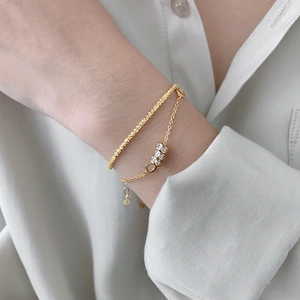 Elegant double-layered gold bracelet with sparkling cubic zirconia cylinders on wrist