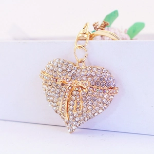 Golden heart keychain with butterfly knot and crystal inlay on a minimalist white setup