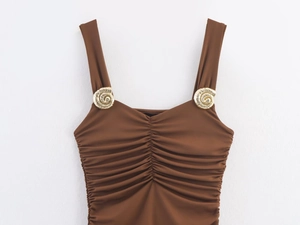 Detail of brown one-piece swimwear with gold shell ornaments on the shoulder straps
