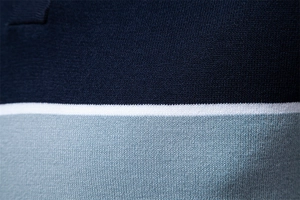 Detailed close-up of a three-color spliced knit polo shirt with fine texture