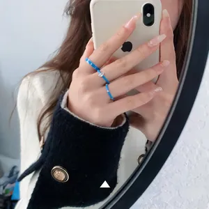 Close-up of blue enamel stackable rings with a teardrop-shaped crystal detail