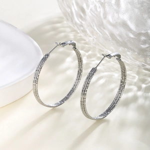 Detail view of silver chain texture hoop earrings on elegant glass and porcelain setting