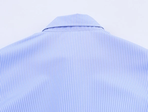 Dettaglio di camicia a righe azzurre che mostra cuciture del colletto e trama del cotone