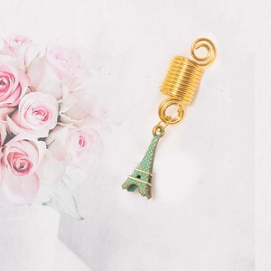 Detail of gold spiral dreadlock ring with a green Eiffel Tower charm pendant