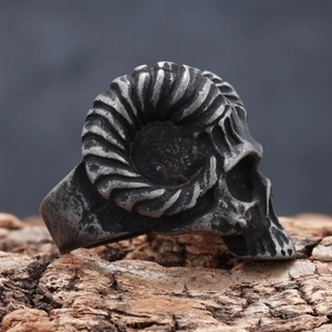 Vintage stainless steel ram skull ring with detailed spiral horns on rustic wood