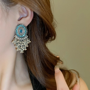 Detail of bohemian silver tassel earrings with blue stones on a female model's ear