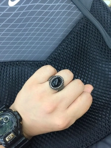 Close-up of vintage stainless steel men's ring with oval black gemstone on finger