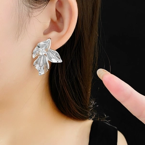 Gros plan d'un mannequin portant des boucles d'oreilles pétales en argent sur fond noir
