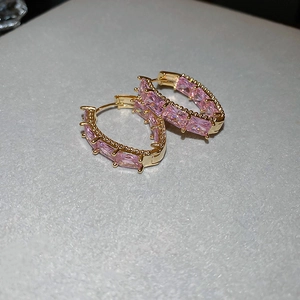 Detail of gold-plated geometric hoop earrings with pink rectangular zircon stones