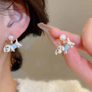 Detail of cute dog earrings with white enamel, pearls, and crystals on a female ear