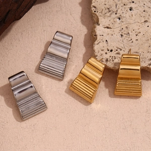 Detailed view of gold and silver trapezoid wave earrings on minimalist background