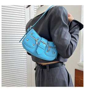 Close-up of bright blue retro biker shoulder bag with silver studs and metal buckles