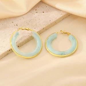 Detail of light blue marble resin hoops with gold metal edges on a textured stone surface