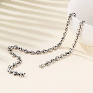 Close-up of silver stainless steel coffee bean link chain resting on a ceramic bowl