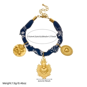 Retro blue fabric bracelet with gold sacred heart and floral charms on a white background