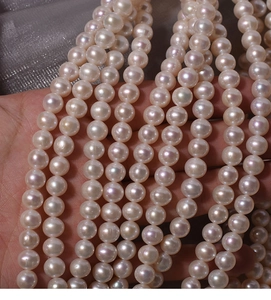 Close-up of 7mm creamy white natural freshwater pearls with lustrous finish on grey silk