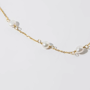 Macro shot of 925 silver gold chain with white round pearls in a minimalist design