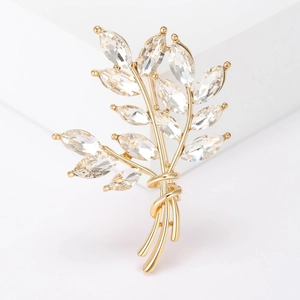 Close-up of elegant wheat stalk brooch with gold base and marquise-cut crystals