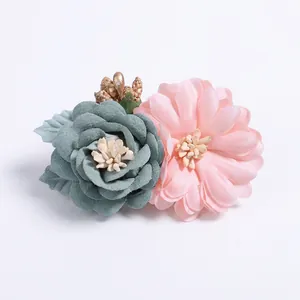 Detail of fabric rose and daisy hair clip with delicate beads and golden accents