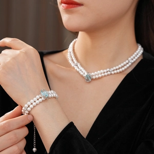 Détail d'un collier et d'un bracelet double rang en perles avec pendentifs en zircon bleu