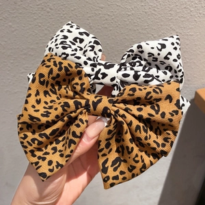 Detailed texture of white and brown leopard print bow hair clips in textured fabric