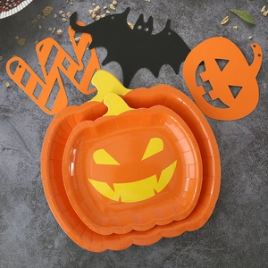 Detail of Halloween pumpkin shaped paper plates and bat cutout decorations on a dark table