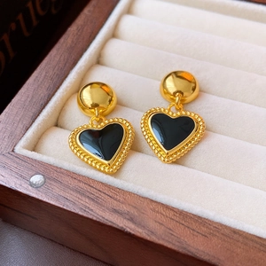 Detail of vintage heart earrings with black enamel in a beige velvet jewelry box