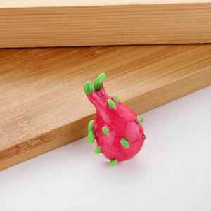Detail view of pitaya fruit brooch with vibrant magenta resin and green leaf accents