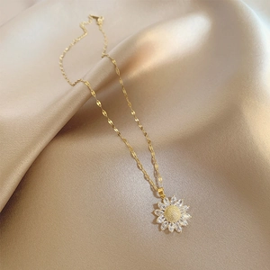 Macro detail of golden sunflower pendant with marquise zircon petals on silk