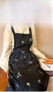 Detailed embroidery of colorful flowers on a black cotton seersucker apron for women