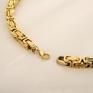 Close-up of golden stainless steel Byzantine chain necklace with lobster clasp detail